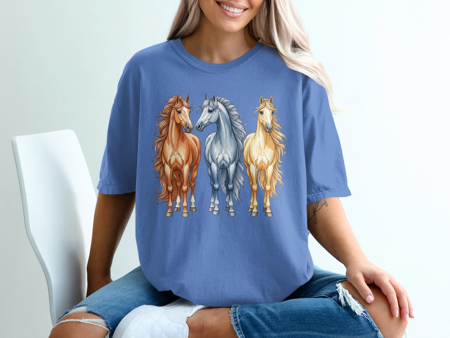 Three horses, one brown, one grey, one white, printed on a blue t-shirt.