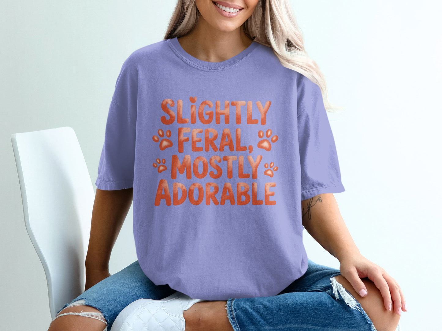 Lavender t-shirt with "Slightly Feral, Mostly Adorable" and paw print text.