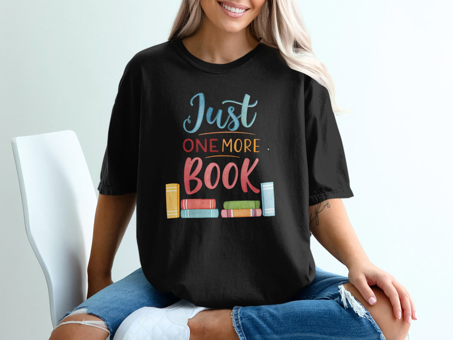 Black t-shirt with "Just ONE MORE BOOK" text and colorful book spine graphic.