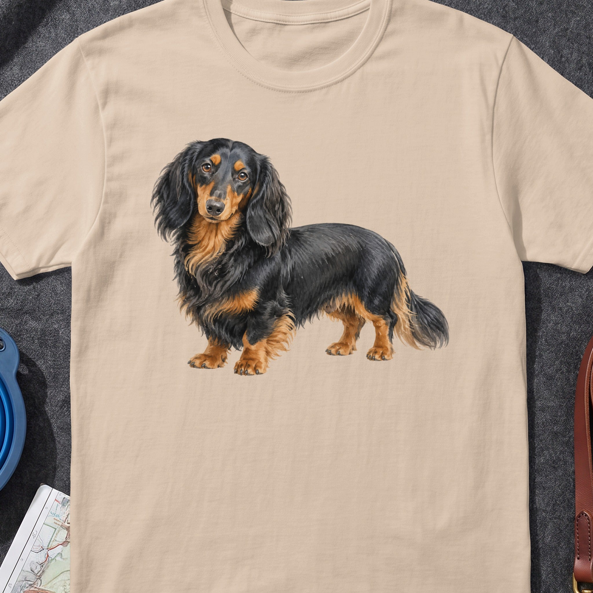 Beige t-shirt with a long-haired black and tan dachshund illustration centered.