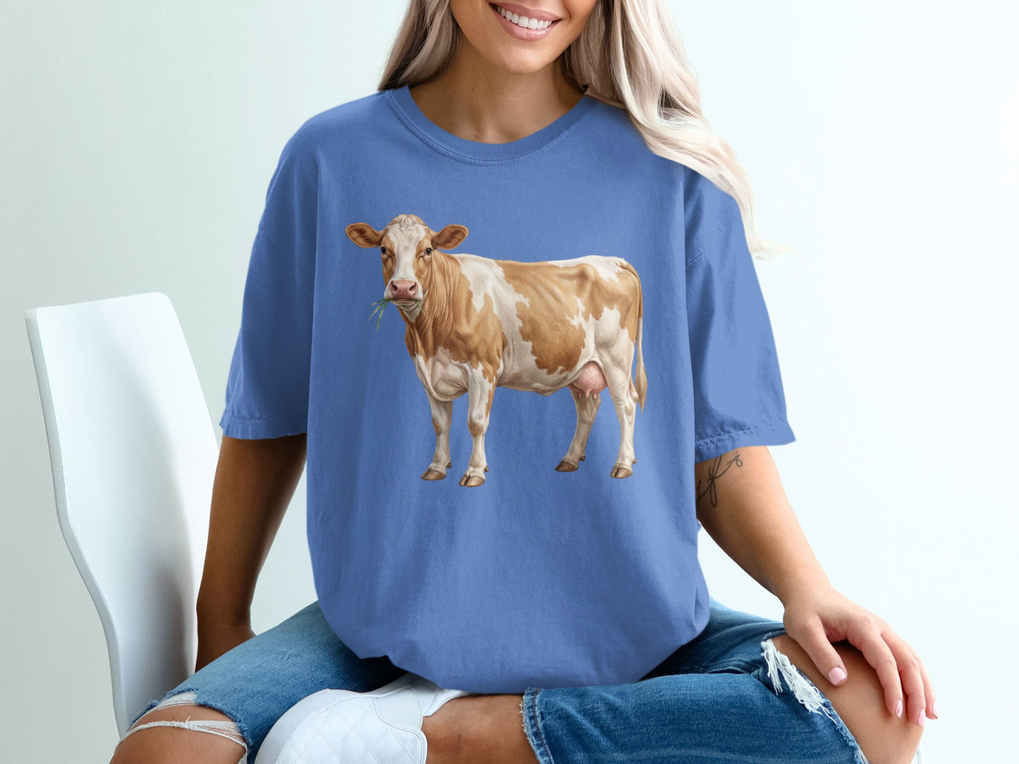 Brown and white cow eating grass, printed on a blue t-shirt.