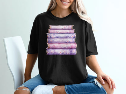 Stack of six pink and purple books with floral accents on a black t-shirt.
