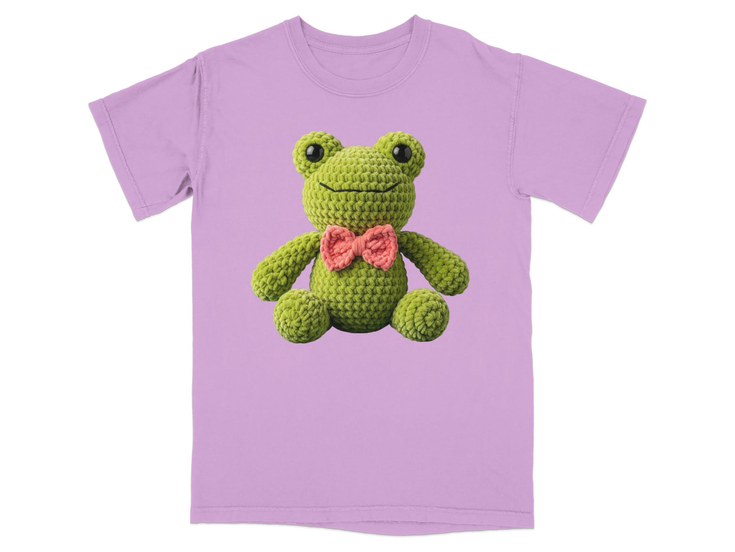 Crocheted green frog with pink bowtie on a lavender t-shirt.