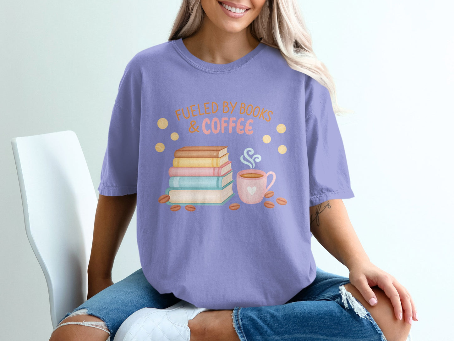 Purple t-shirt with books, coffee cup, and text "Fueled by Books & Coffee".