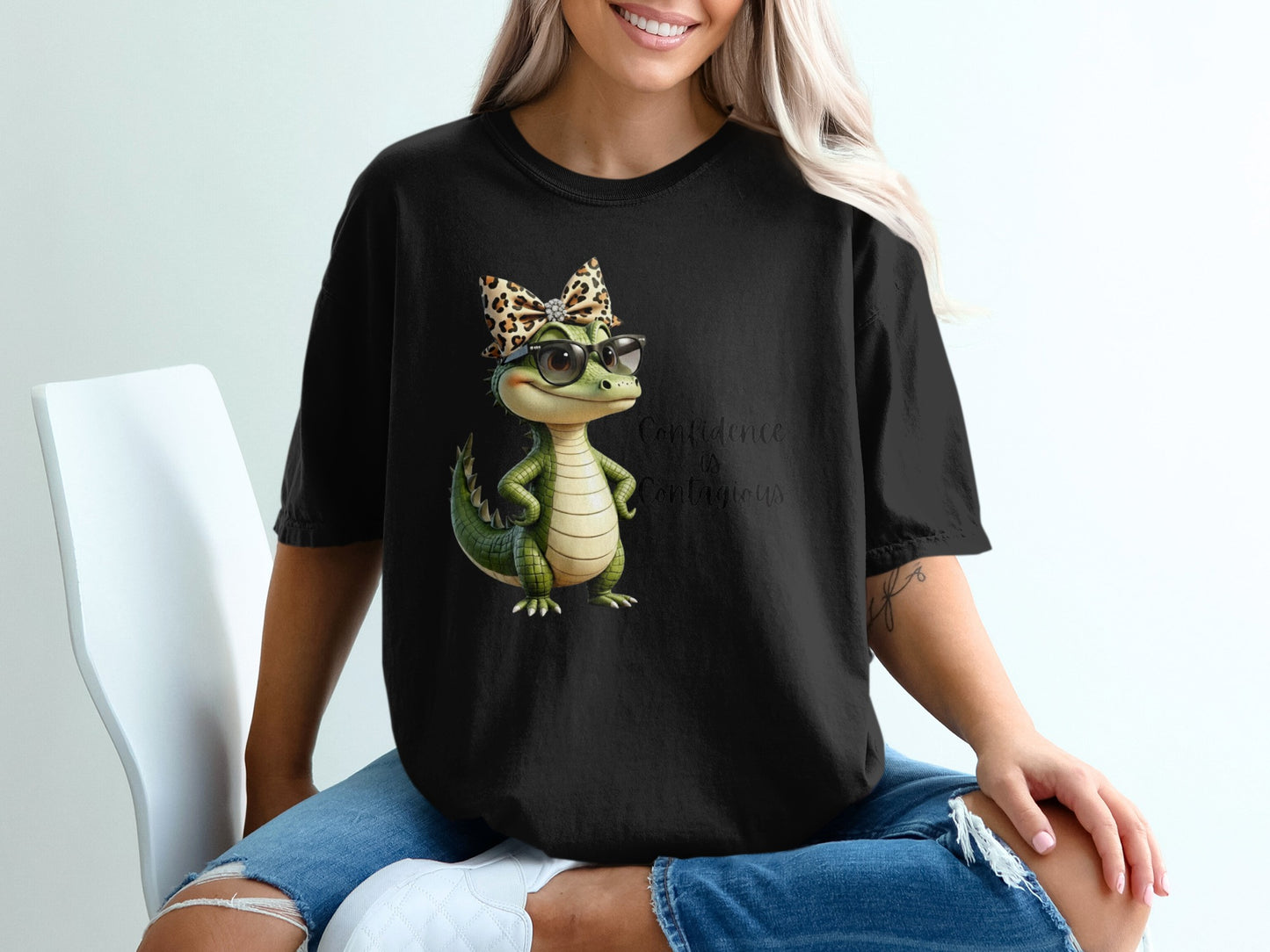 Black t-shirt with cartoon alligator wearing glasses and a leopard print bow.