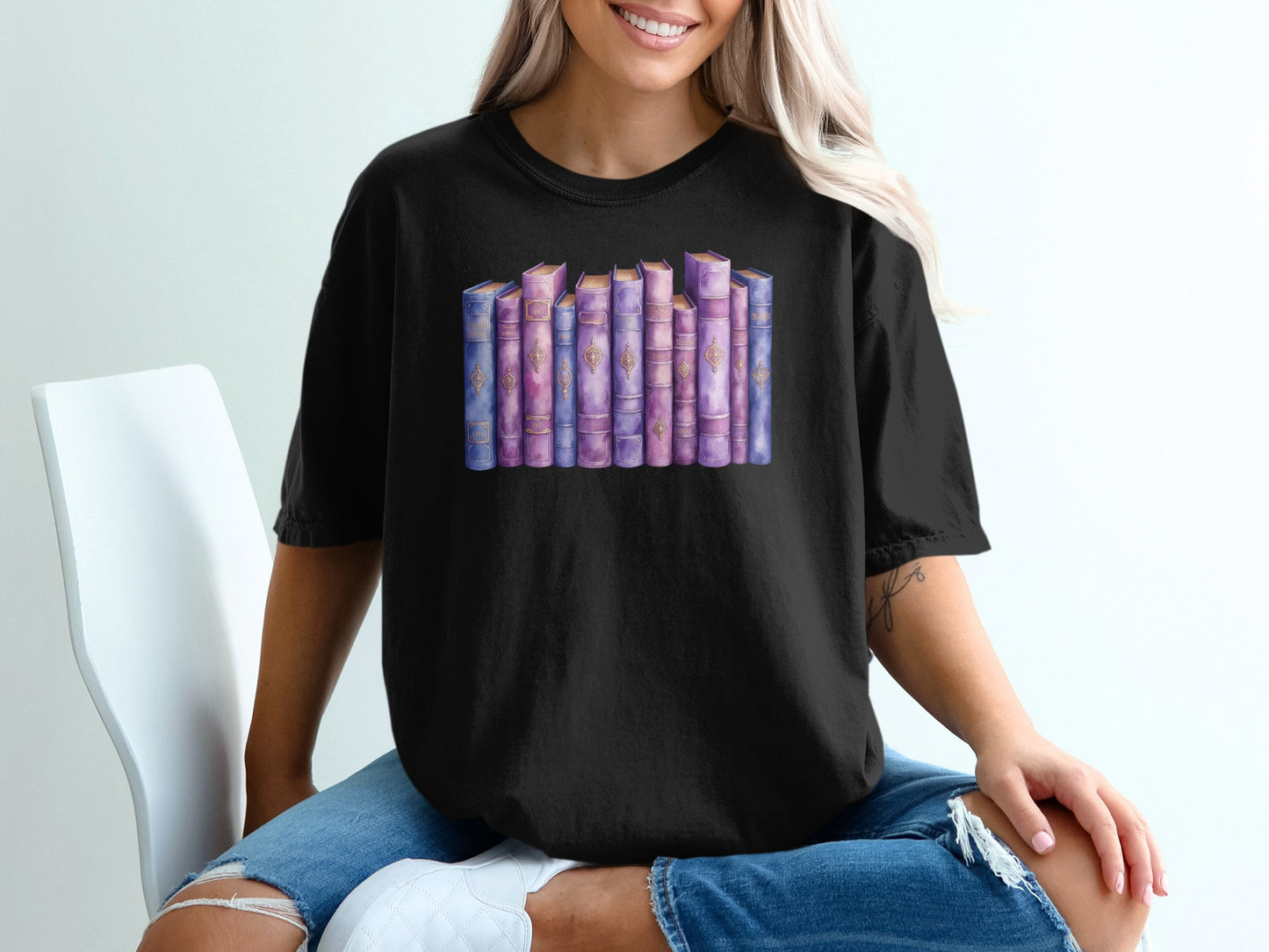 Black t-shirt with watercolor illustration of a shelf of purple and pink books.