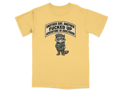 T-shirt with raccoon graphic and text "Another day, another Fucked Up Adventure in Adulthood".