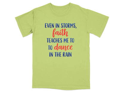 Light green t-shirt with blue and red text "Even in storms, faith teaches me to dance in the rain."