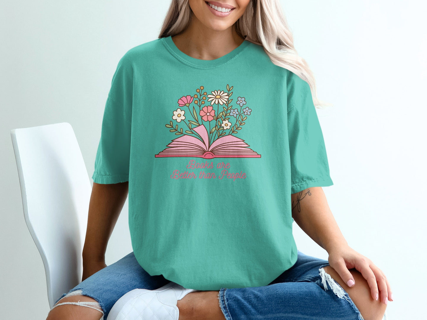 Teal t-shirt with open book and flowers, text reads "Books are better with people".