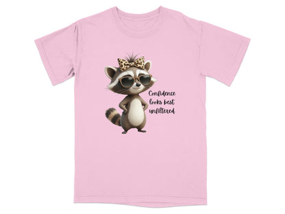 Pink t-shirt with raccoon wearing sunglasses and bow, text "Confidence looks best unfiltered".