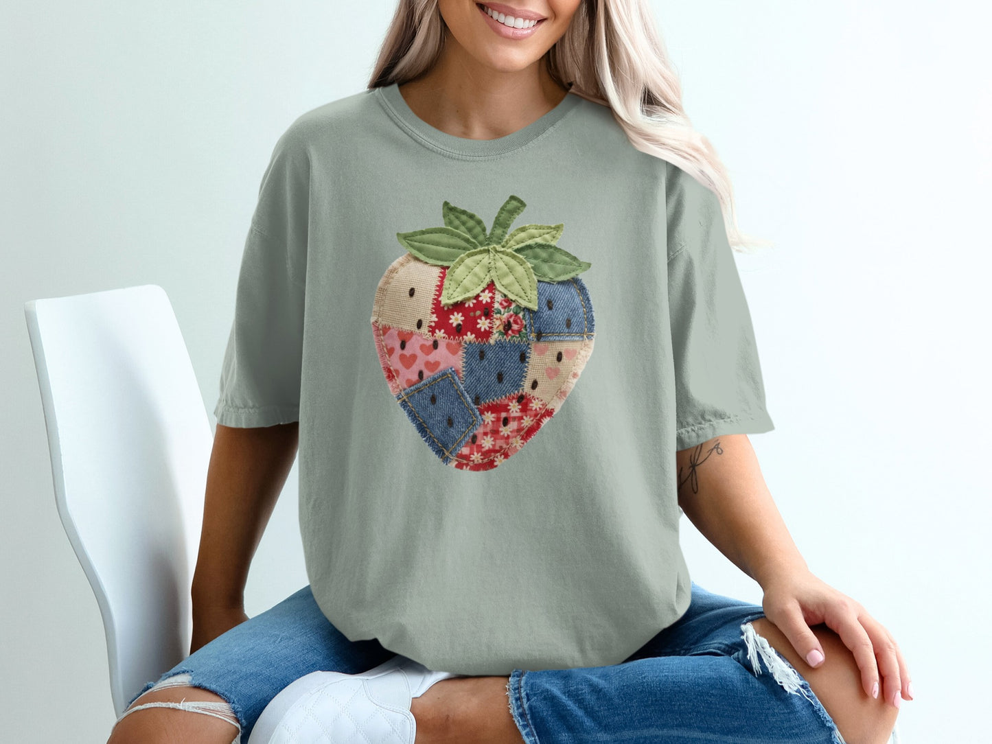 T-shirt with a patchwork strawberry design on a person sitting.