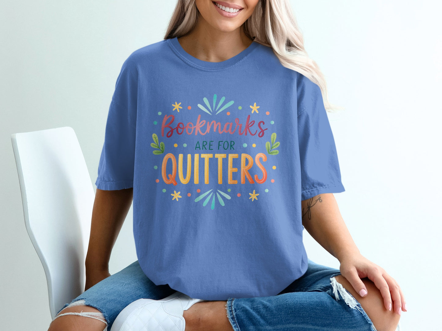 Blue t-shirt with "Bookmarks are for quitters" text and colorful designs.