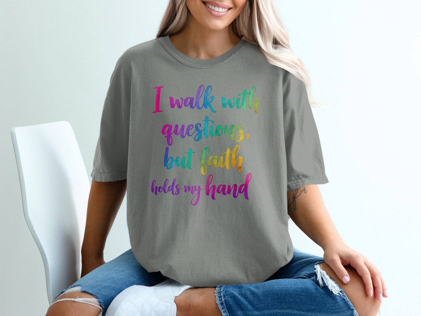Grey t-shirt with rainbow text "I walk with questions, but faith holds my hand."