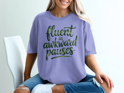 Purple t-shirt with "fluent in awkward pauses" text in green brush strokes.