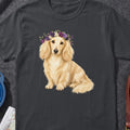 Dachshund wearing a floral crown sits on a dark grey t-shirt.