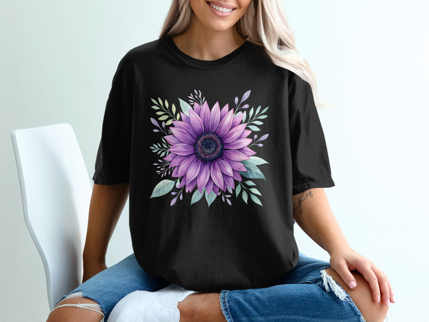 Black t-shirt with a large purple sunflower and green leaves graphic.