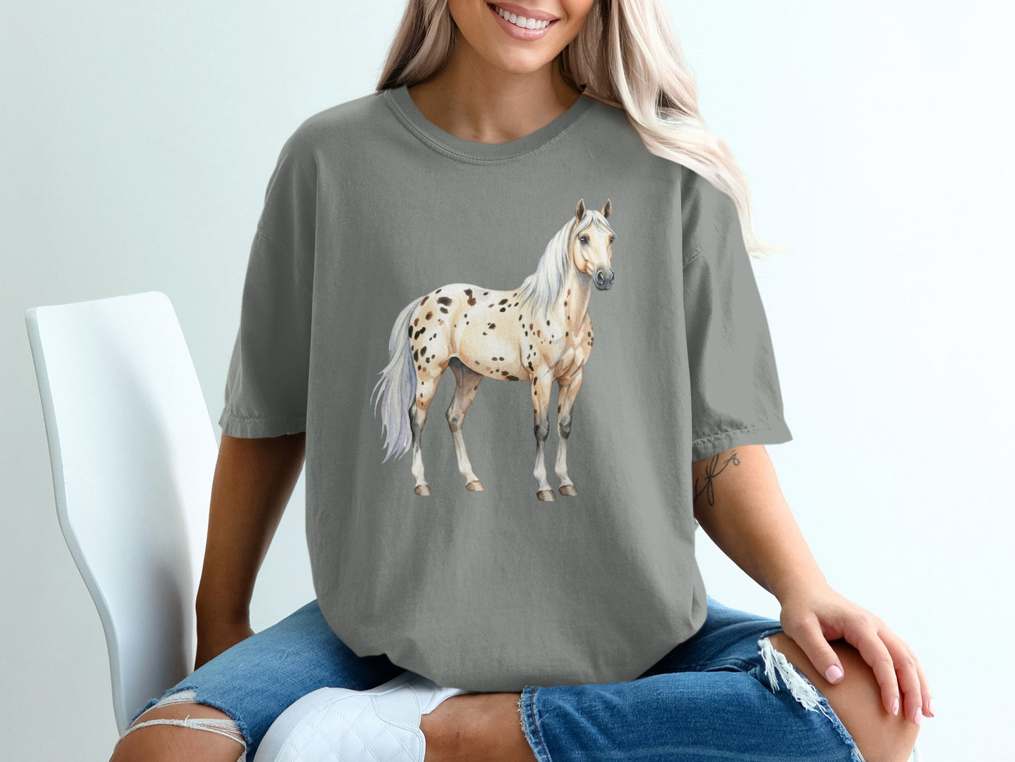 Appaloosa horse illustration on a gray t-shirt worn by a seated person.