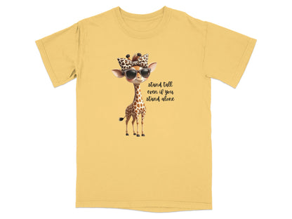 Yellow t-shirt with a cartoon giraffe wearing sunglasses and a bow, text reads "stand tall even if you stand alone".