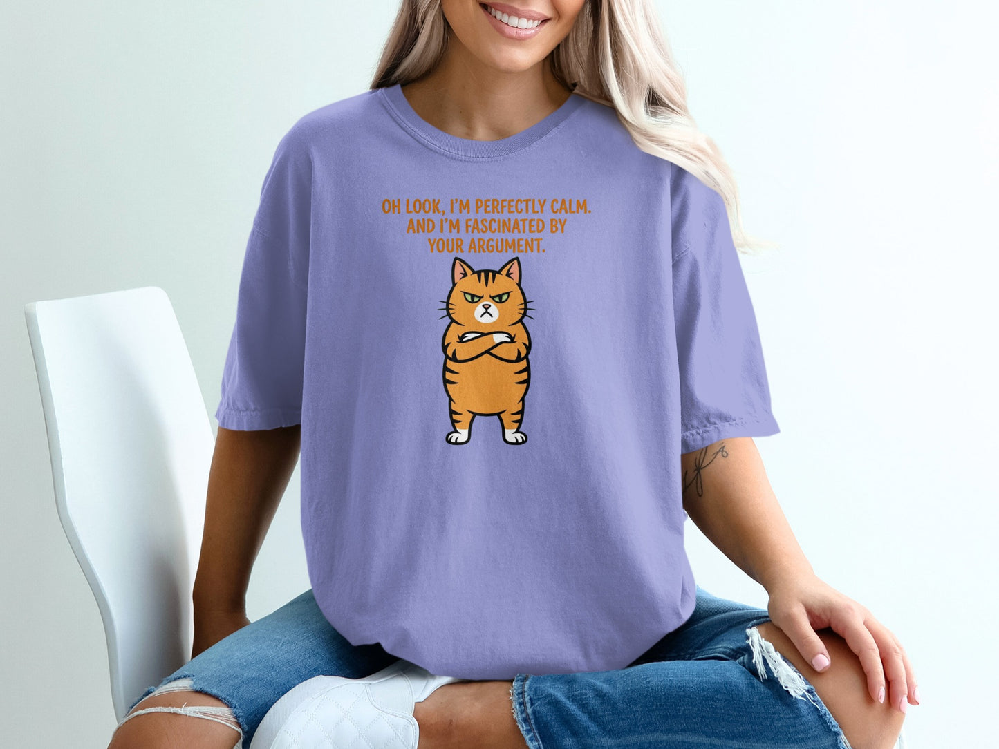 Purple t-shirt with a grumpy orange cat and text "OH LOOK, I'M PERFECTLY CALM. AND I'M FASCINATED BY YOUR ARGUMENT."