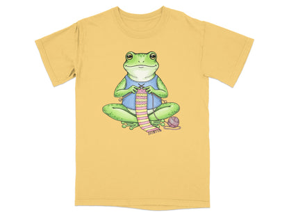 Illustration of a frog knitting a pink and green striped scarf.