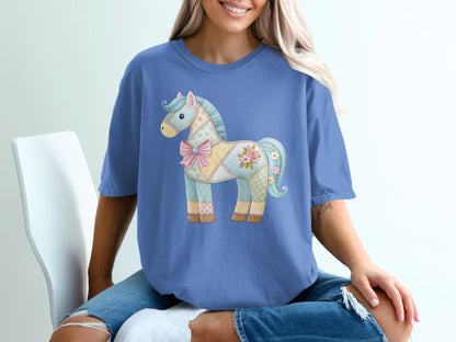 Blue t-shirt with a pastel patchwork horse graphic and pink bow.