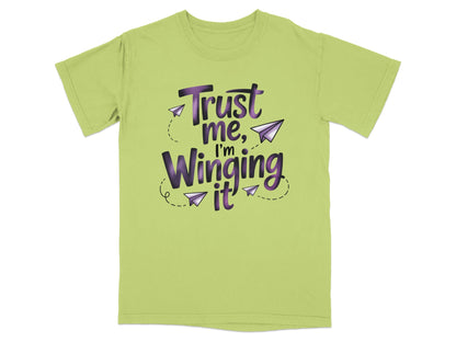Light green t-shirt with purple text "Trust me, I'm Winging it" and paper airplanes.