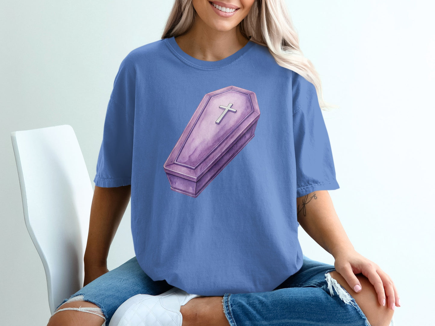 Purple coffin graphic with cross on blue t-shirt.
