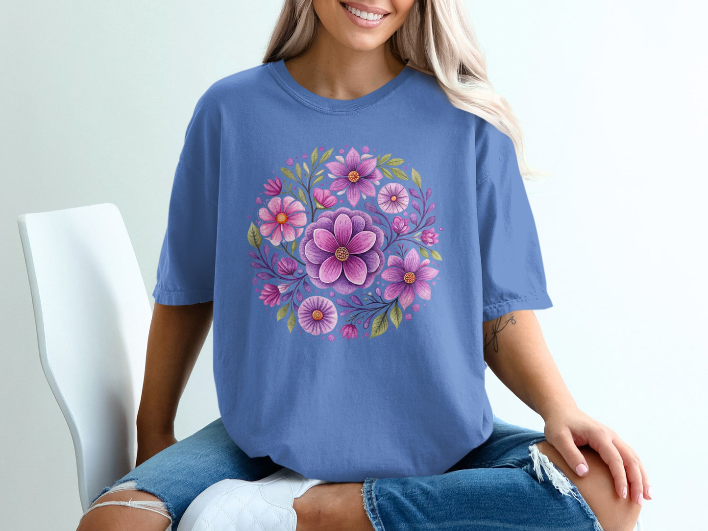 Blue t-shirt with a circular floral design featuring pink and purple flowers and green leaves.
