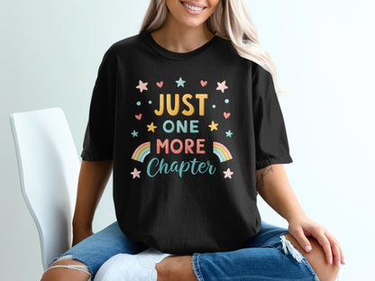 Black t-shirt with "Just One More Chapter" text and rainbow stars