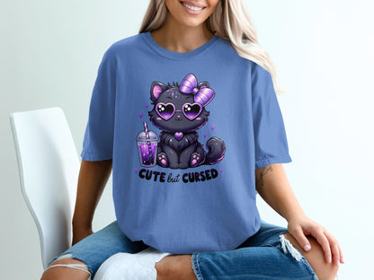 Cute black cat with heart sunglasses and bow on purple t-shirt saying "cute but cursed".