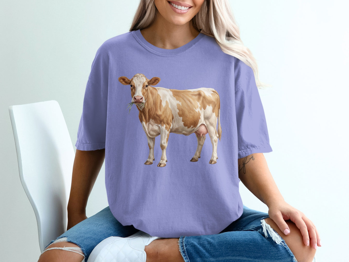 Purple t-shirt with a brown and white cow illustration.