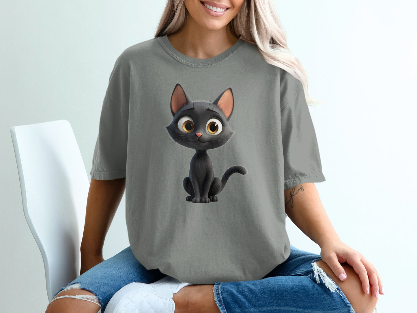 Cartoon black cat with big yellow eyes on a gray t-shirt.