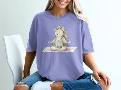 Hedgehog meditating in green robe on yoga mat, wearing purple t-shirt.