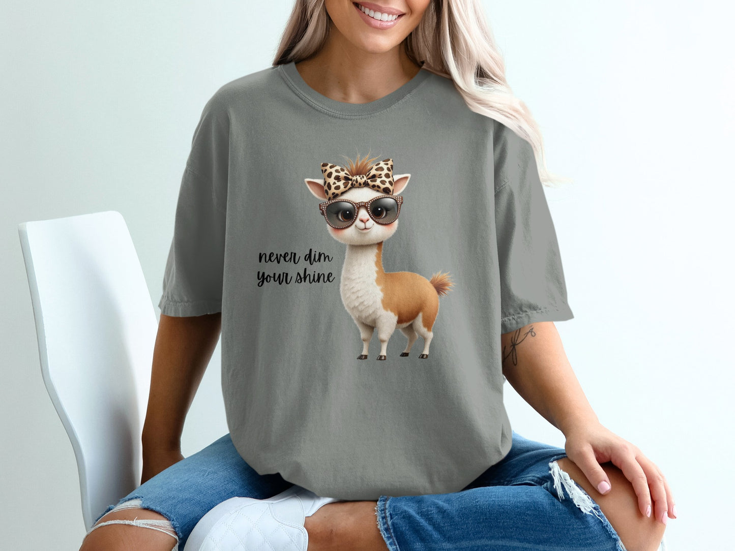 Woman wearing a gray t-shirt with a llama wearing sunglasses and a bandana.