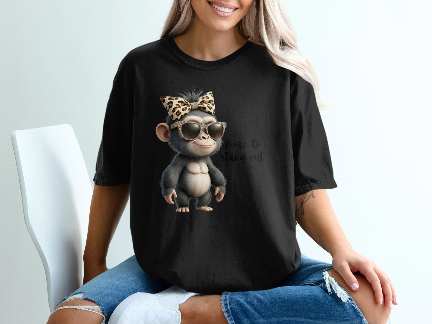 Black t-shirt with graphic of a monkey wearing sunglasses and a bow, text "Born to stand out".