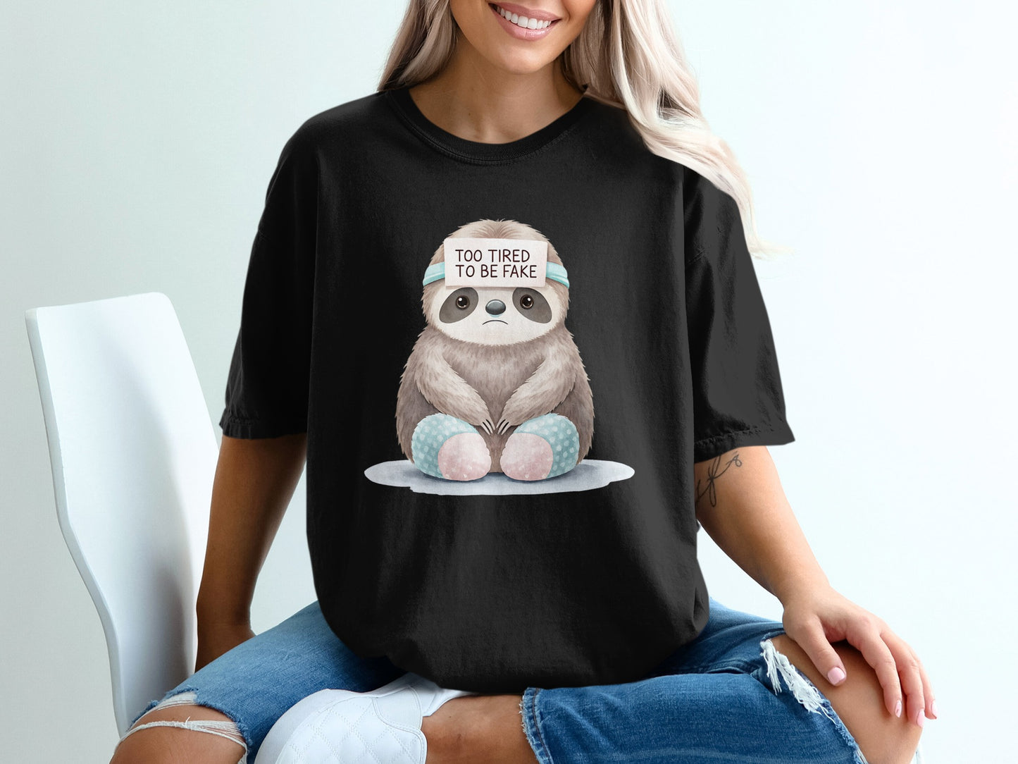 Black t-shirt with a tired sloth wearing a headband that says "TOO TIRED TO BE FAKE".