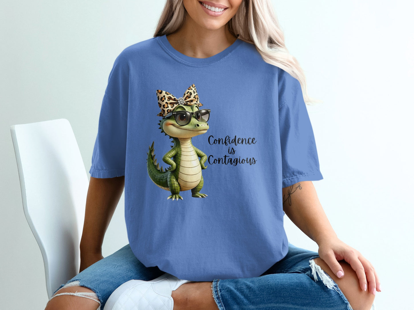 Cartoon alligator in glasses and leopard print bow on a blue t-shirt.